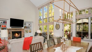A spacious living room with a fireplace, a large dining table, and a view of the outdoors through large windows. - Beaver Creek Enclave | 5BR Home, Summer AC, Hot Tub (Beaver Creek)