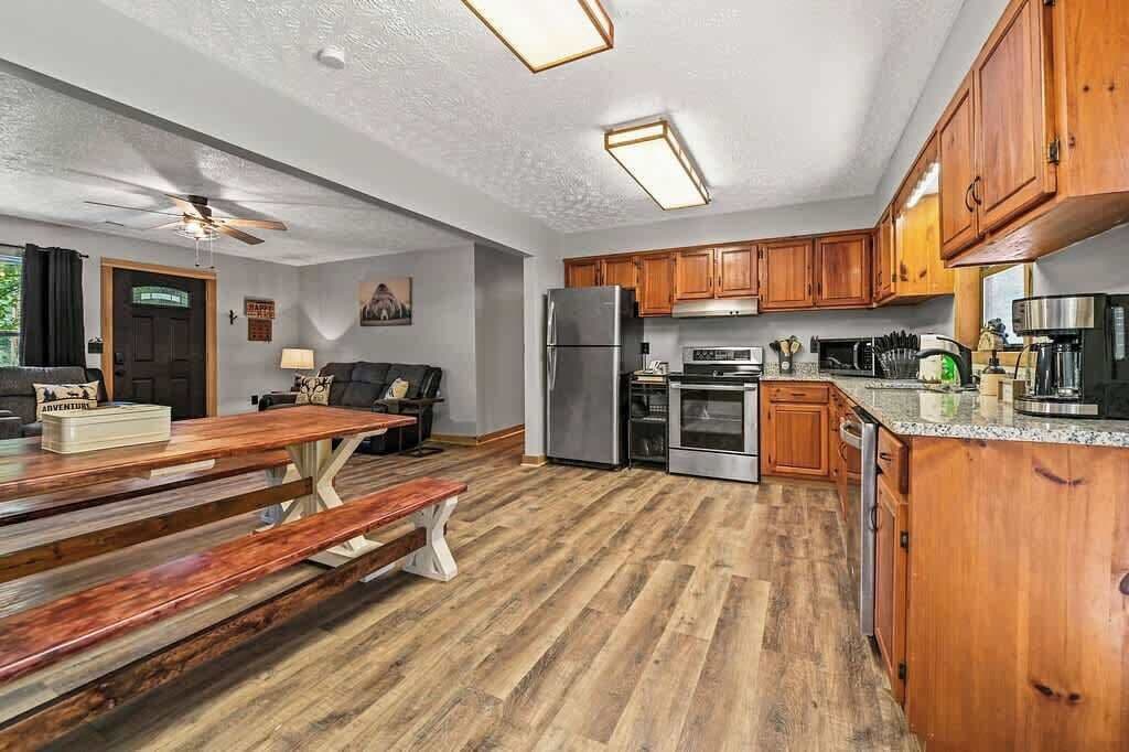 A spacious kitchen with wooden cabinets, a stainless steel refrigerator, and a granite countertop.