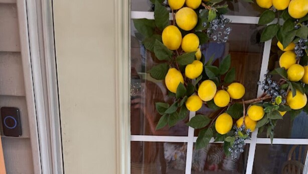 En hoveddør med et kode lås, en pyntelig fugl og en krans af citroner og blade.