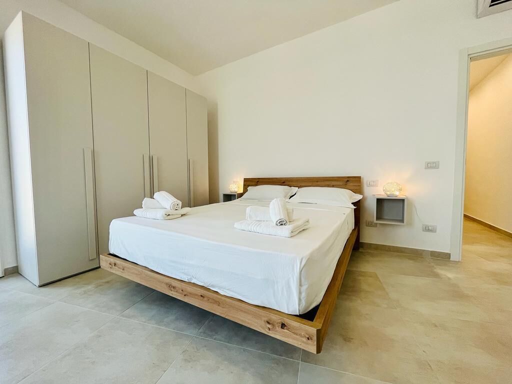 A bedroom with a wooden bed frame, white bedding, and a large wardrobe.