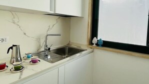 A small kitchen with a sink, a window, and a view of a building outside. - Dimora San Felice - I limoni (Gallipoli)