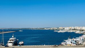 A marina with boats docked, a clear blue sky, and a cityscape in the background. - Dimora San Felice - I limoni (Gallipoli)