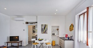Un espacio habitable compacto con comedor, kitchenette y televisor.