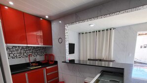 Una cocina moderna con armarios rojos, una encimera negra y un salpicadero blanco.