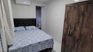 Un dormitorio con cama, armario y aire acondicionado.