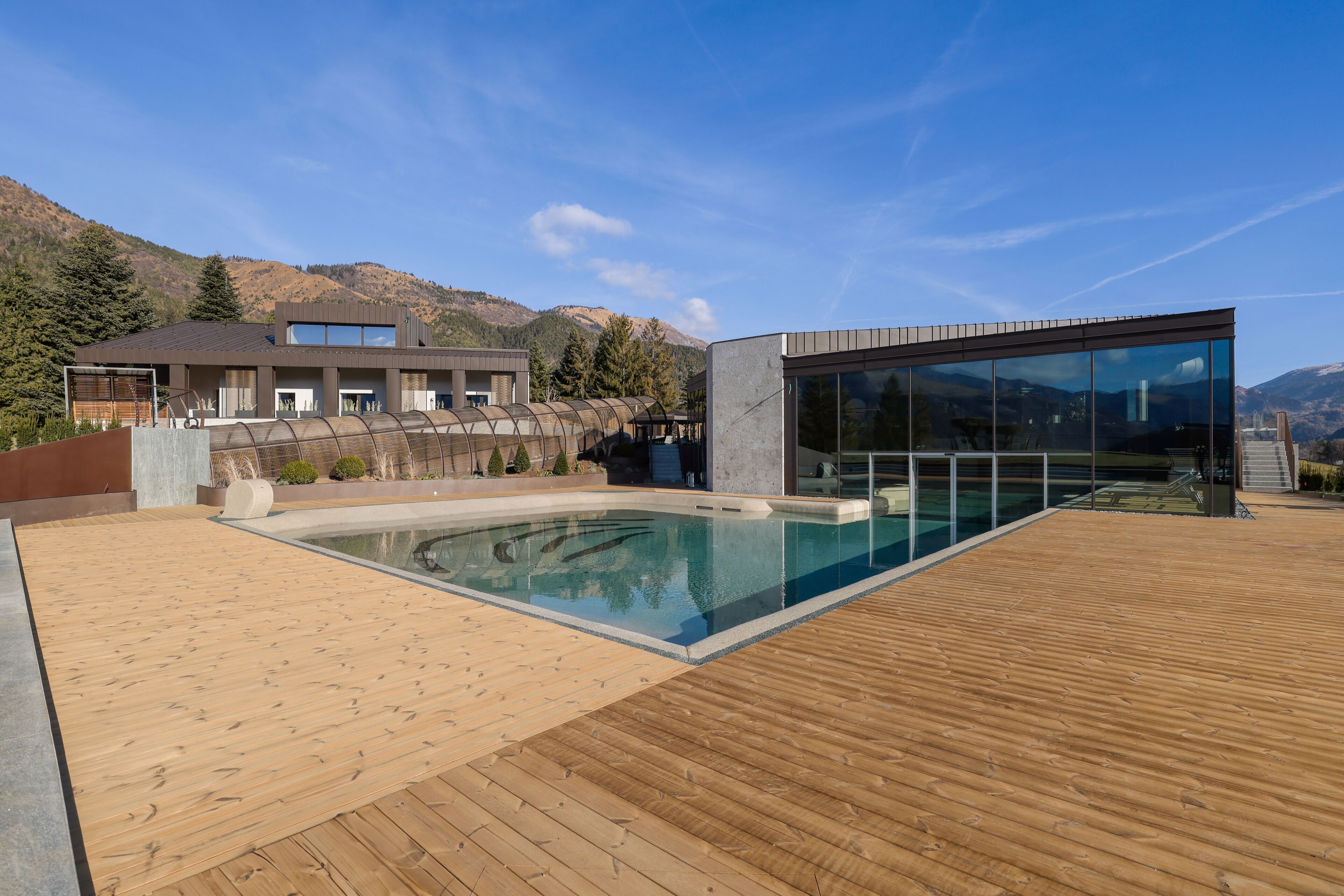 Un bâtiment moderne doté d’une piscine et d’une terrasse en bois.