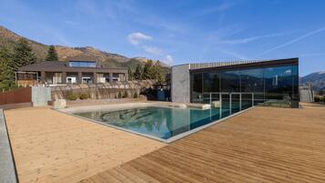 Un bâtiment moderne doté d’une piscine et d’une terrasse en bois.