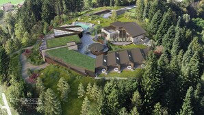 An aerial view of a residential area with modern houses, a large green field, and dense forest. - Collina Luxury Relais  (Clusone)