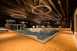 An indoor swimming pool with wooden flooring and circular light fixtures. - Collina Luxury Relais  (Clusone)