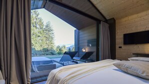 A bedroom with a bed, a TV mounted on the wall, and a view of the outdoors. - Collina Luxury Relais  (Clusone)