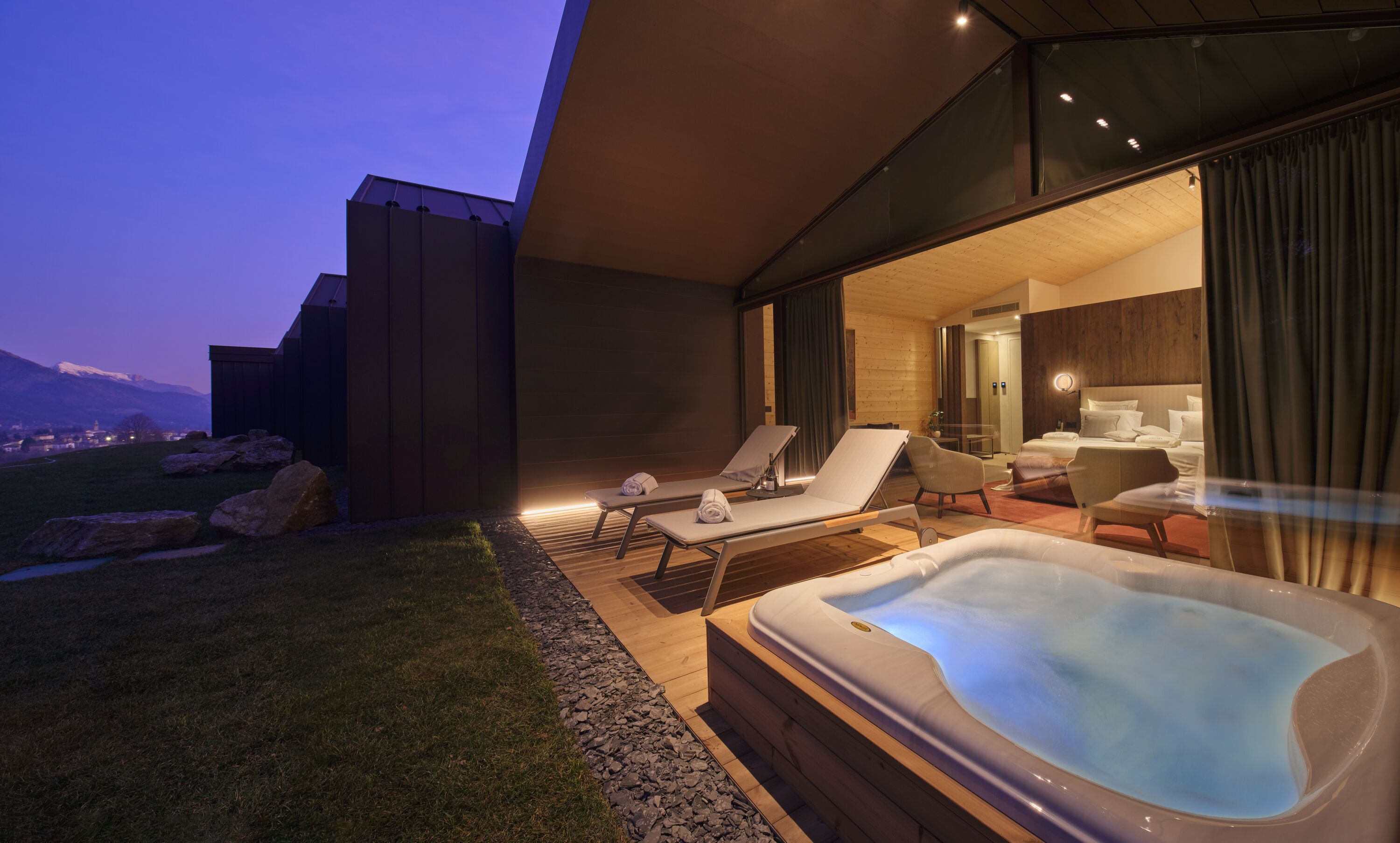 Un espacio moderno al aire libre para relajarse con un jacuzzi, sillones de descanso y vistas a una cordillera.