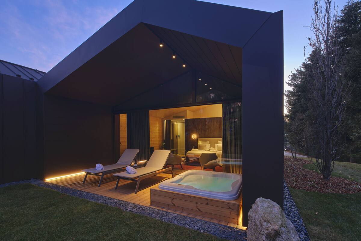 Una casa moderna amb un bany d'hidromassatge, gandules i un interior ben il·luminat.