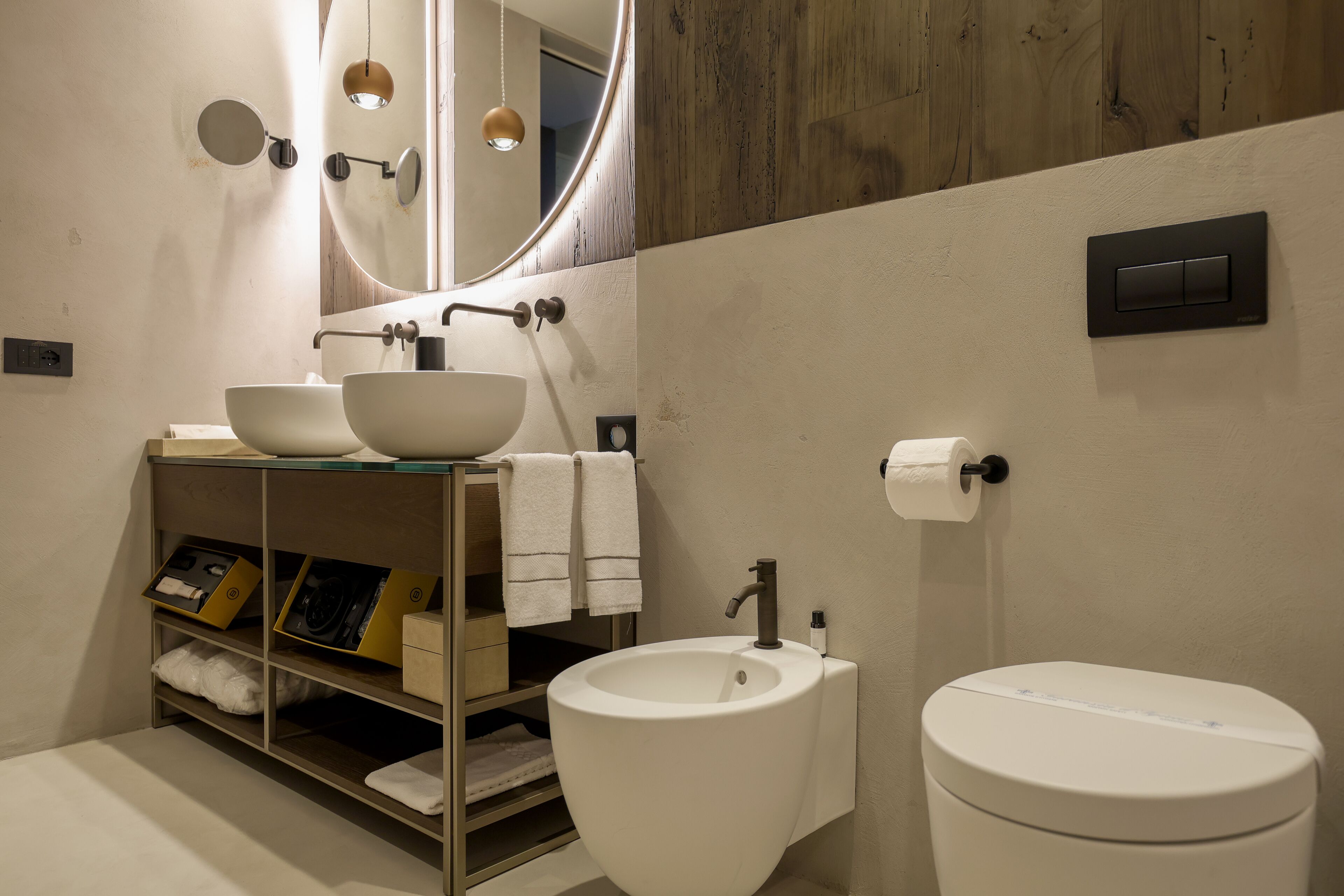Une salle de bain moderne avec un grand miroir, deux lavabos, des toilettes et un porte-serviettes.