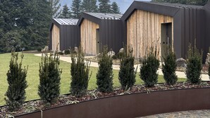 A modern building with a wooden facade and a stone patio area. - Collina Luxury Relais  (Clusone)