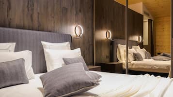 Un dormitorio moderno con una cama grande, ropa de cama gris y blanca, y luces empotradas en la pared.