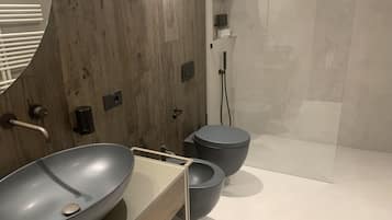 Un baño moderno con tocador de madera, un lavamanos grande tipo recipiente y un inodoro separado.
