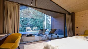 A modern bedroom with a large sliding glass door leading to a balcony. The room features a bed, a yellow chair, and a small table.