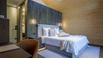 Un dormitorio moderno con techo de madera, una cama grande con ropa blanca, mesitas de noche y un escritorio con una computadora portátil.