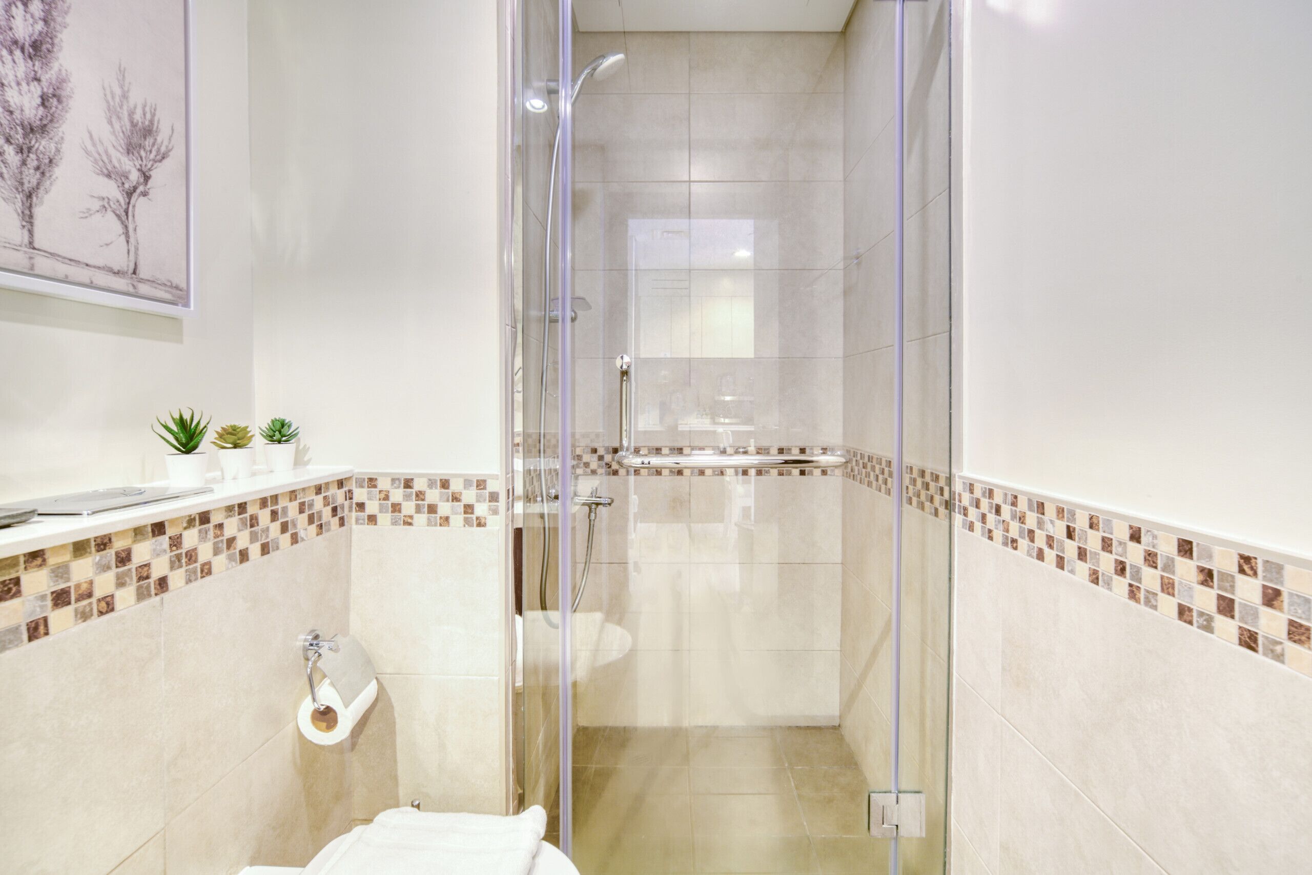 A modern bathroom with a glass shower enclosure, a toilet, and a sink.