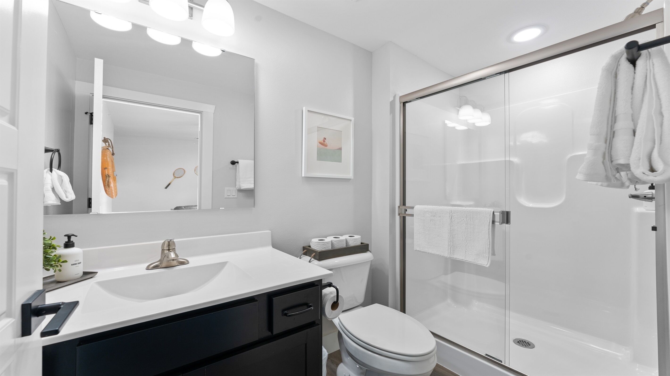 A modern bathroom with a white sink, a toilet, and a glass-enclosed shower.