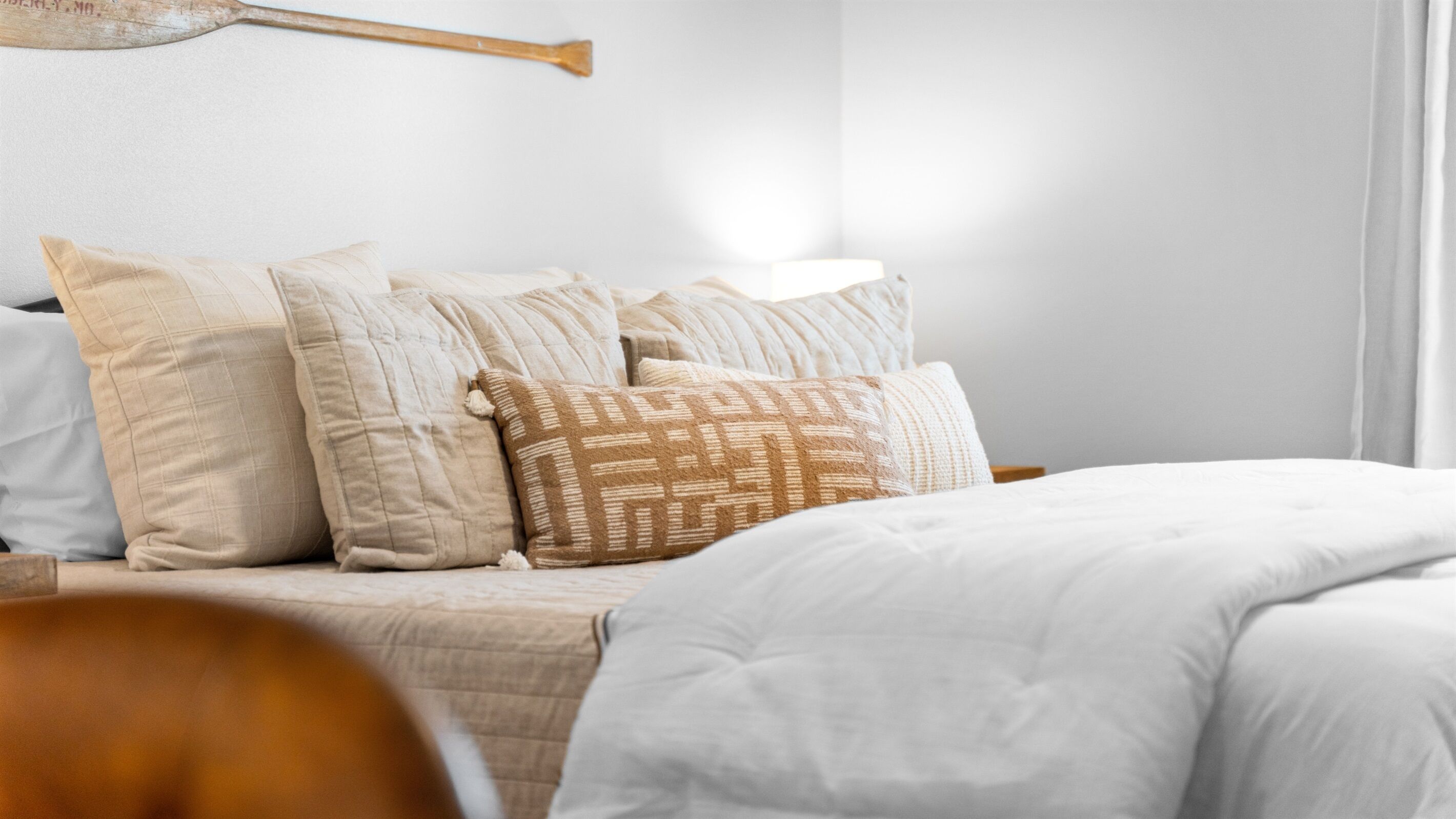 Un lit bien fait, agrémenté de plusieurs oreillers, dans une pièce au design simple et épuré.