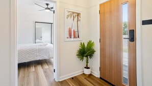 Ein Hotelzimmer mit einem Bett, einem Deckenventilator, einer Topfpflanze und einer Holztür.