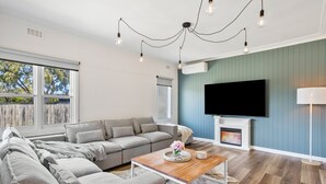Ein modernes Wohnzimmer mit einer Eckcouch, einem Holztisch, einem Kamin und einem flachbildfernseher an der Wand.