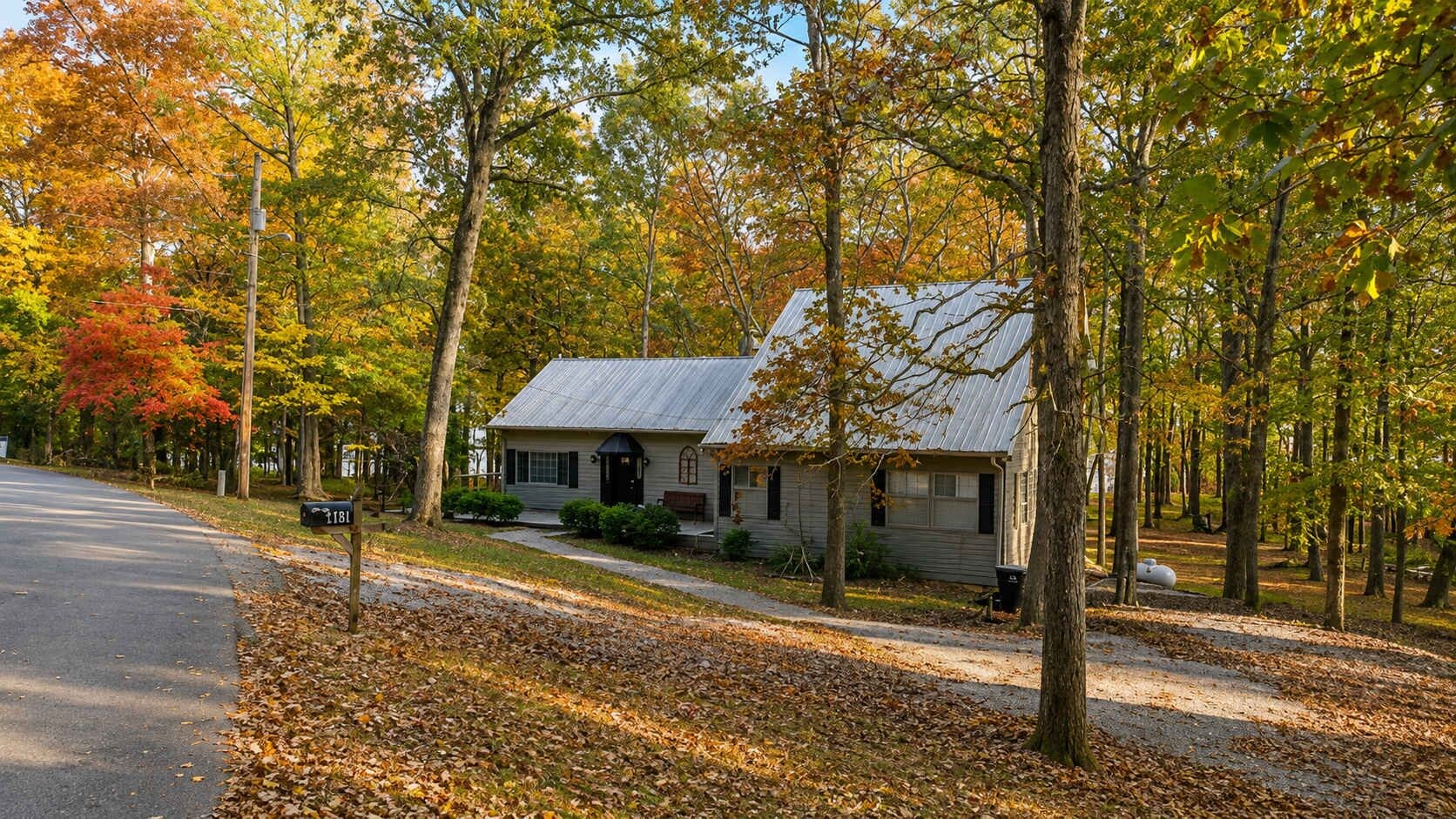 A two-story house with a metal roof, surrounded by trees with autumn foliage.