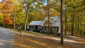A two-story house with a metal roof, surrounded by trees with autumn foliage. - Lakefront Haven • Dock, Fishing & Swim (Cadiz)