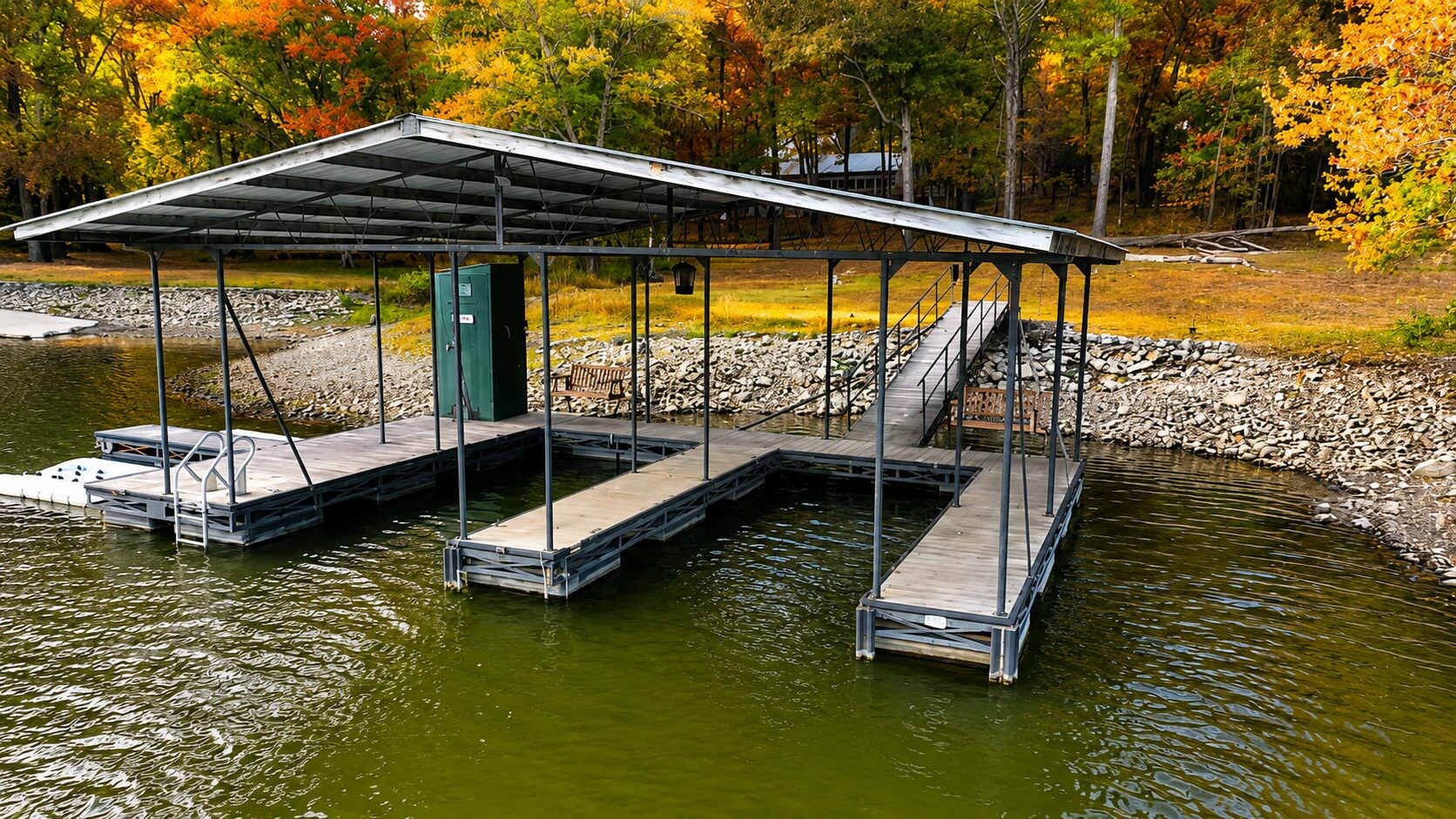A dock with a covered area, a green utility box, and a wooden bench.
