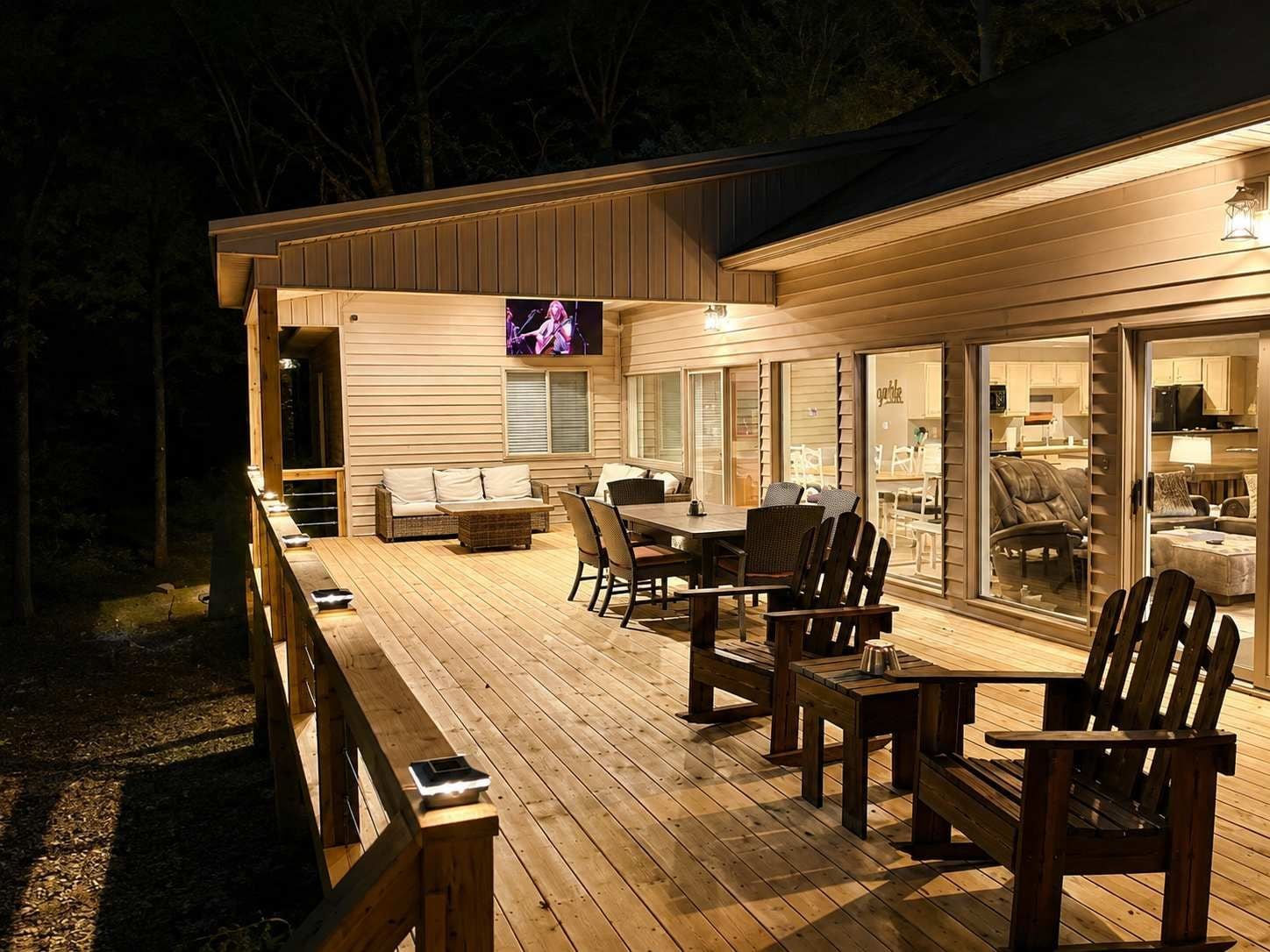 An outdoor deck with a dining area, seating, and a television screen.