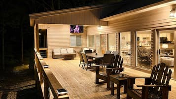 An outdoor deck with a dining area, seating, and a television screen.