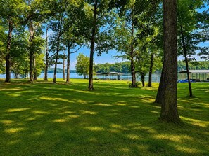 Um parque com vista para um lago, árvores e um pavilhão coberto.