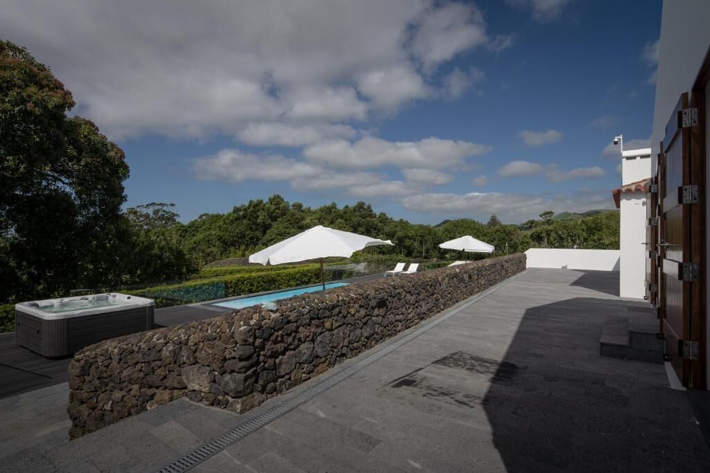 Terraza en la azotea con jacuzzi, piscina y sombrillas blancas.