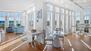 A spacious room with large windows, a dining area, and a view of the ocean.