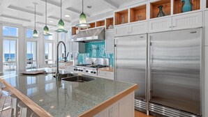 A modern kitchen with a large island, stainless steel appliances, and pendant lighting.