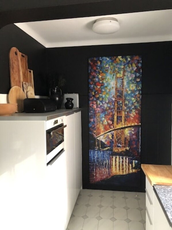 A modern kitchen with a white countertop, a built-in oven, and a colorful abstract painting on the wall. - Beautiful Villa, seaview, pool, babypool, biggarden, Pentaque/Badminton/pingpong (Lagoa)