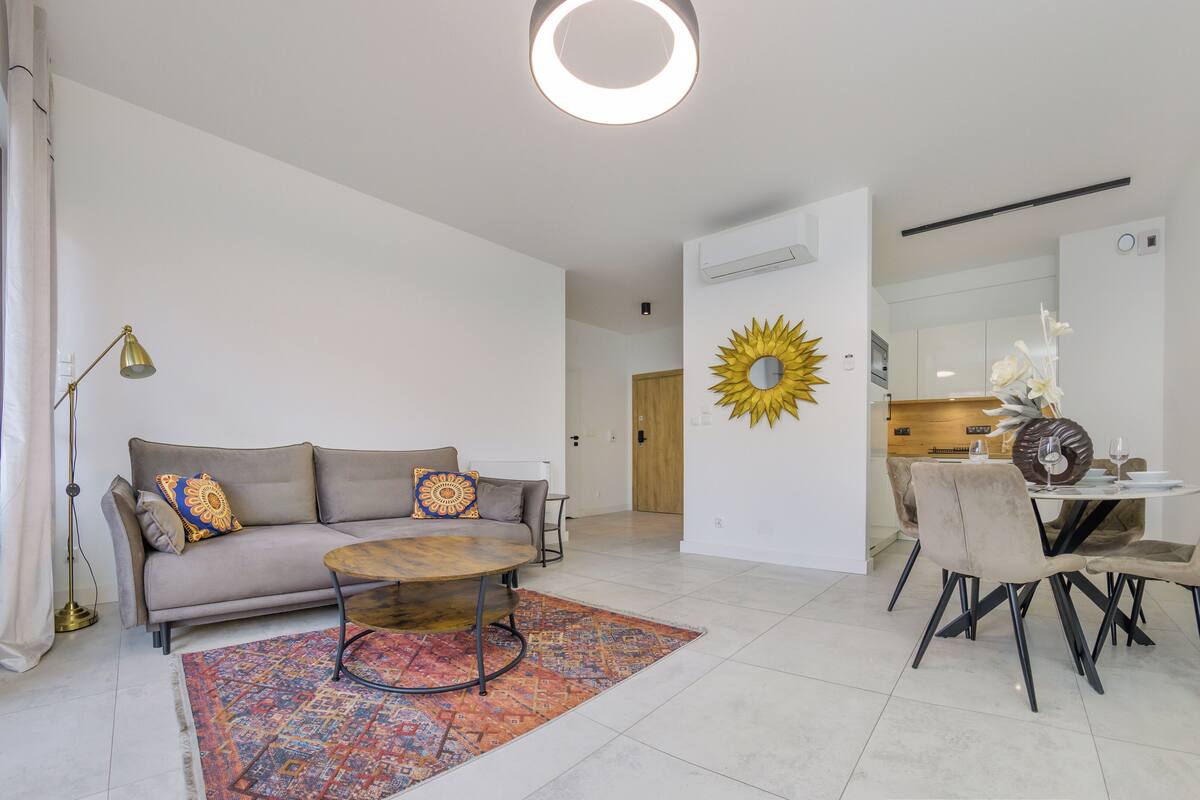 A modern living room with a sofa, coffee table, and dining area.