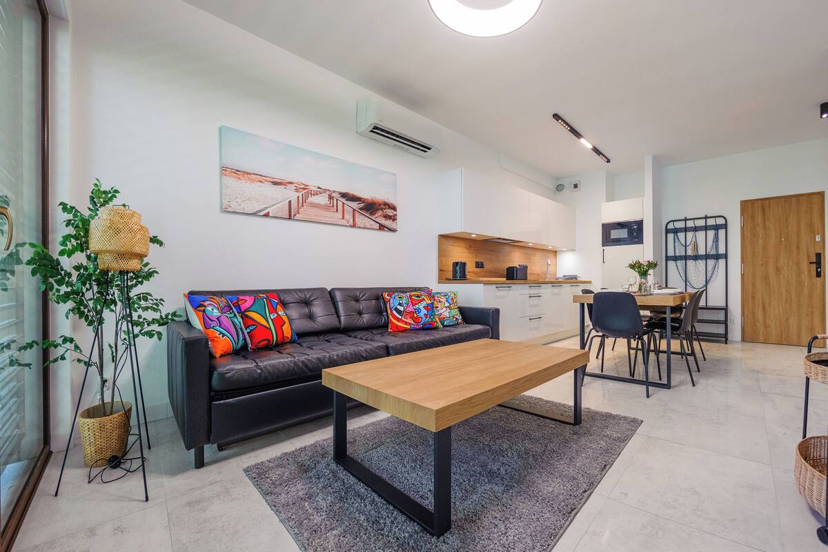 A modern living room with a sofa, coffee table, and dining area.