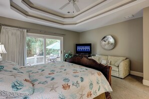 A bedroom with a large bed, a television, a ceiling fan, and a view of the outdoors through a sliding door. - 17 Cartgate - Palmetto Dunes - 4 Bed 4 Bath Private Pool -Hilton Head Rentals (Hilton Head Island)