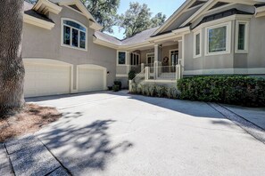 A two-story house with a covered front porch, a garage, and a well-maintained lawn. - 17 Cartgate - Palmetto Dunes - 4 Bed 4 Bath Private Pool -Hilton Head Rentals (Hilton Head Island)