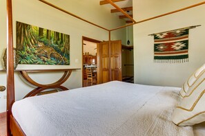 Ein Schlafzimmer mit einem großen Bett, einem Dschungelgemälde und einem Wandteppich.