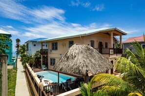 Ein Resort mit Pool, einem strohgedeckten Gebäude und Blick auf den Ozean.