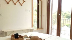 A bedroom with a bed, a bedside table, a mirror, and a view through a large window. - Detached villa within walking distance of Foxi and Murdegu beach (Foxi Murdegu)