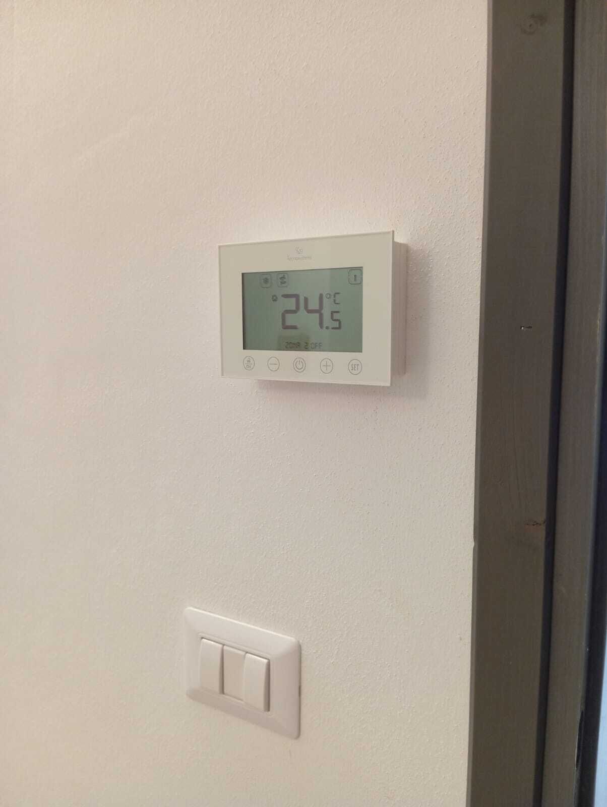 A thermostat displaying 24.5°C and a wall-mounted light switch.