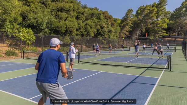 Cancha de tenis con varios jugadores y una red en el centro.