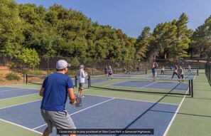 Un court de tennis où plusieurs joueurs s’affrontent, avec un filet au centre.