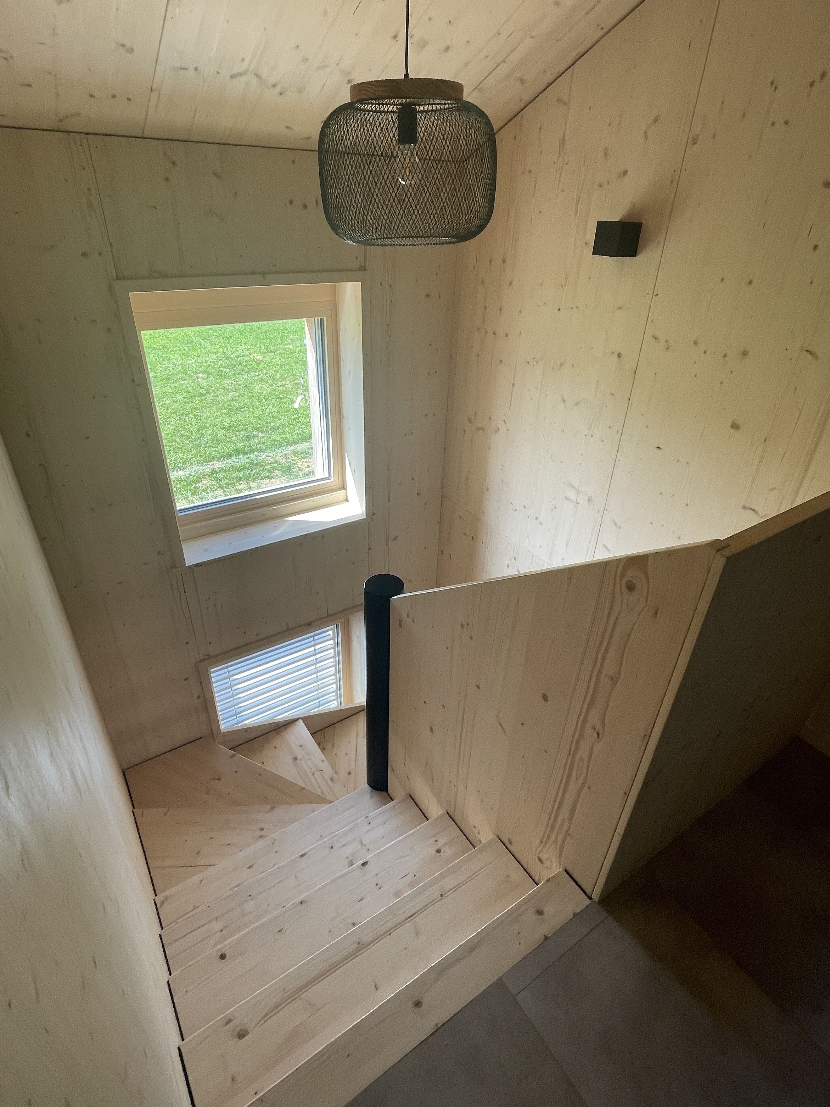 A wooden staircase with a window leading to a grassy outdoor area.