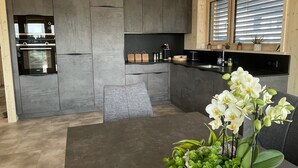 Une cuisine moderne dotée d’un four encastré et d’un coin repas avec une table et des chaises.