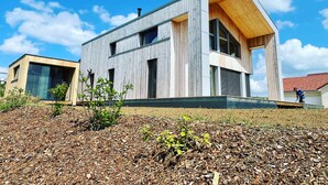 Une maison moderne à deux étages, avec une façade en bois et de grandes fenêtres.